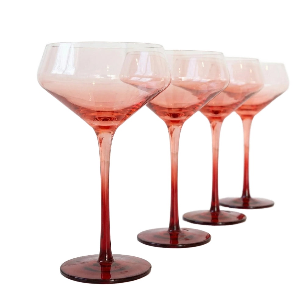 Four stemmed cocktail glasses with a gradient color transition from pale pink at the top to deep red at the base, arranged in a row against a white background.