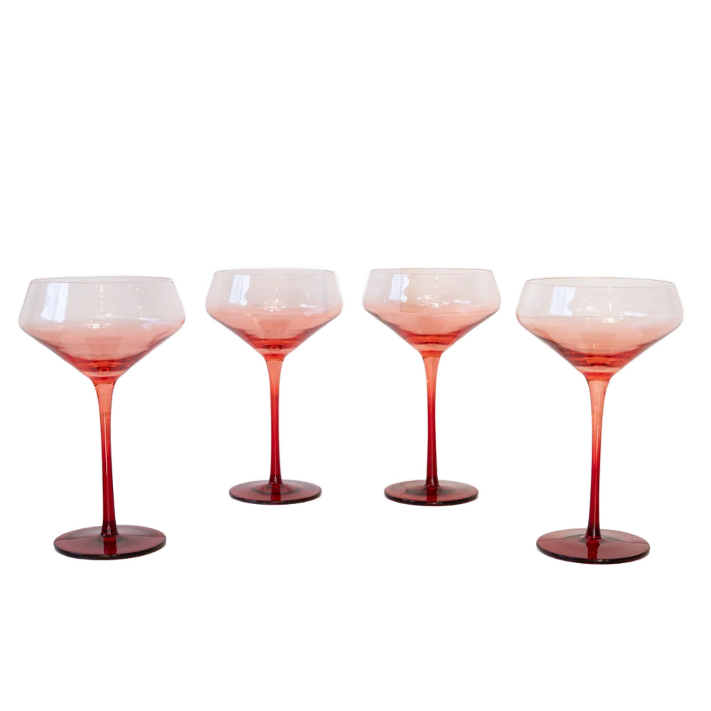 Four stemmed cocktail glasses with a translucent pink-to-red gradient, arranged in a row against a plain white background.