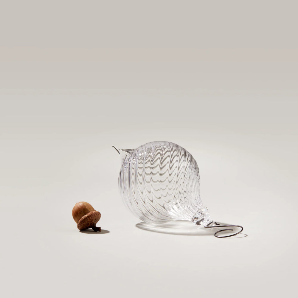 Clear glass hanging ornament with a hook on a semi-dark background