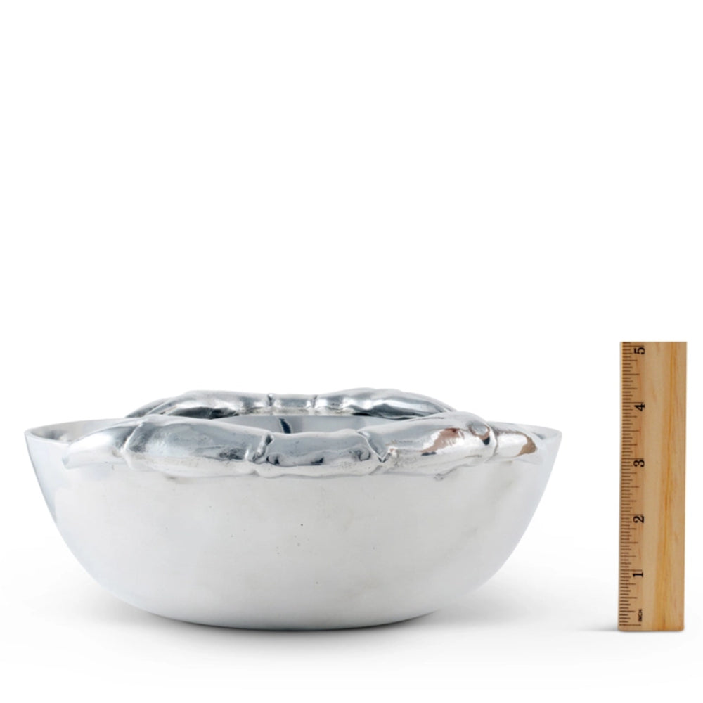 A silver metallic bowl with a textured, hammered finish, shown next to a wooden ruler for scale on a white background.