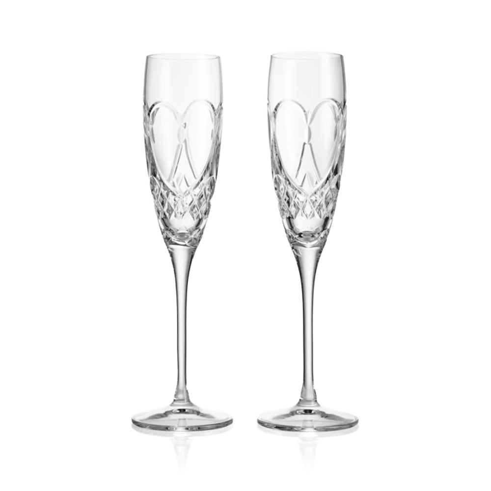 Two crystal champagne flutes with intricate designs on a white background
