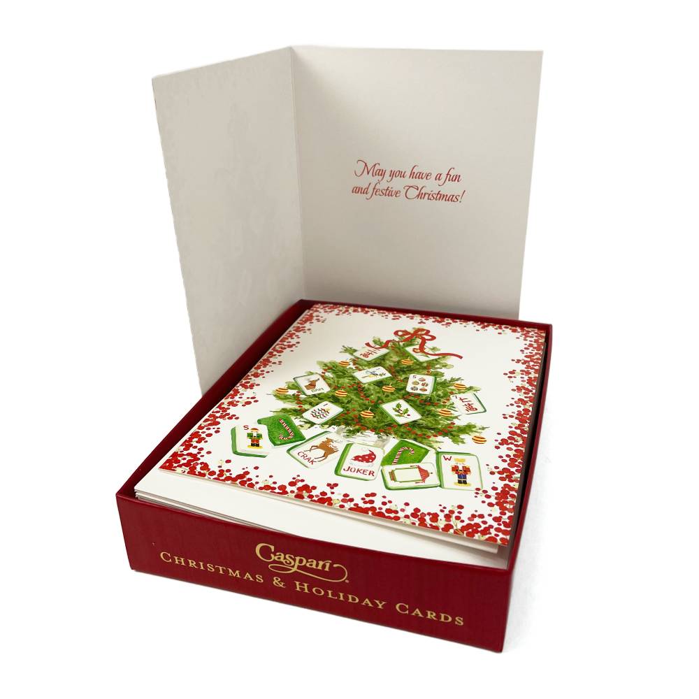 A boxed set of Christmas and holiday greeting cards shown open, with the front card featuring a decorated Christmas tree and hanging ornaments. The box is dark red with gold lettering, and the inside card reads, 'May you have a fun and festive Christmas!' The brand name 'Caspari' is visible on the front of the box.