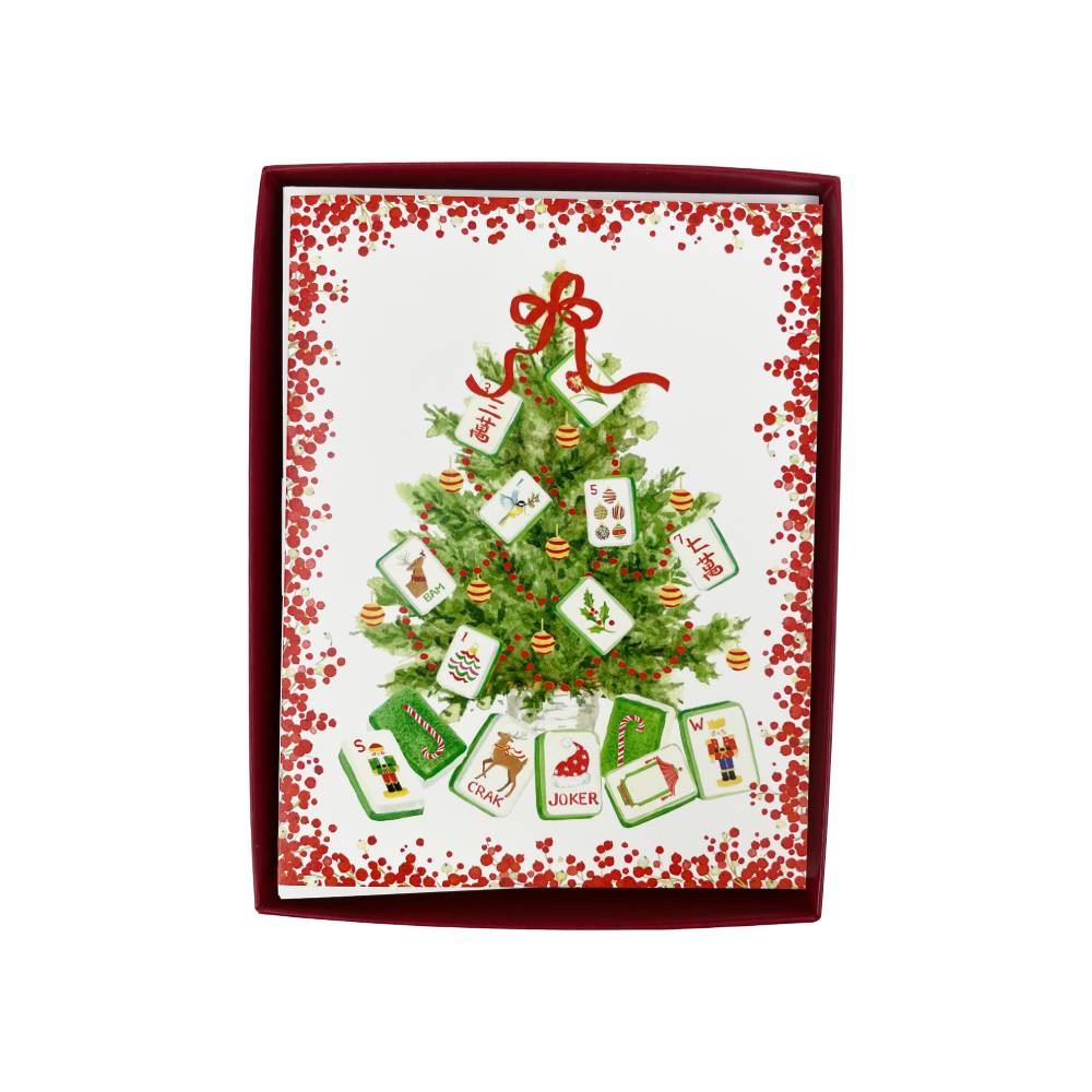 A Christmas-themed greeting card  box featuring an illustrated green Christmas tree decorated with red ornaments and playing cards hanging from it, with a red border and red confetti pattern on a white background.