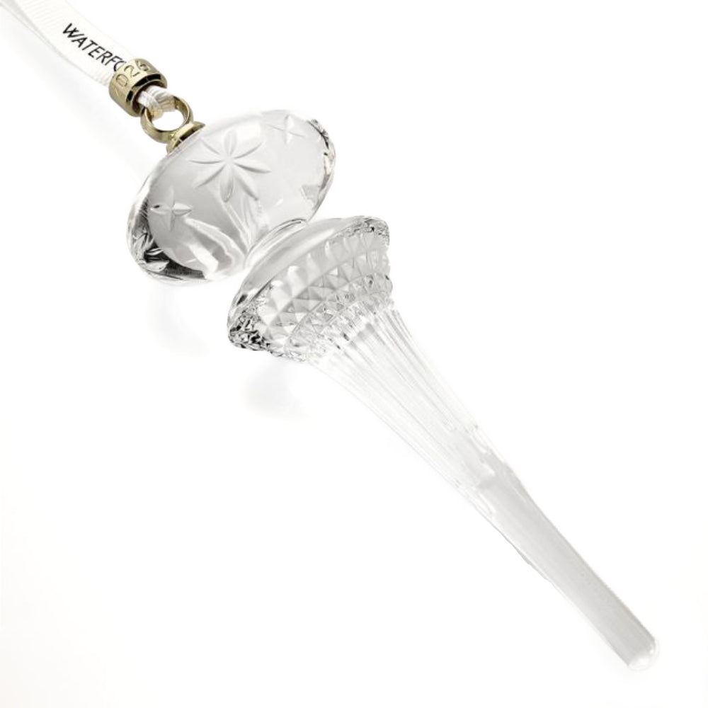 A side photo of the 2026 Waterford Icicle clear glass chrismas ornament with a gold cuff o the hanger with "2026 engraved on it on a with backround 