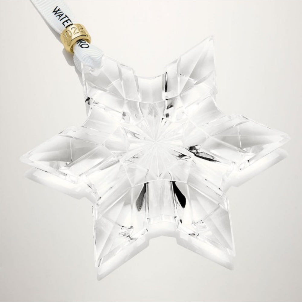 Clear star-shaped crystal ornament with gold accent around ribbon on a white background