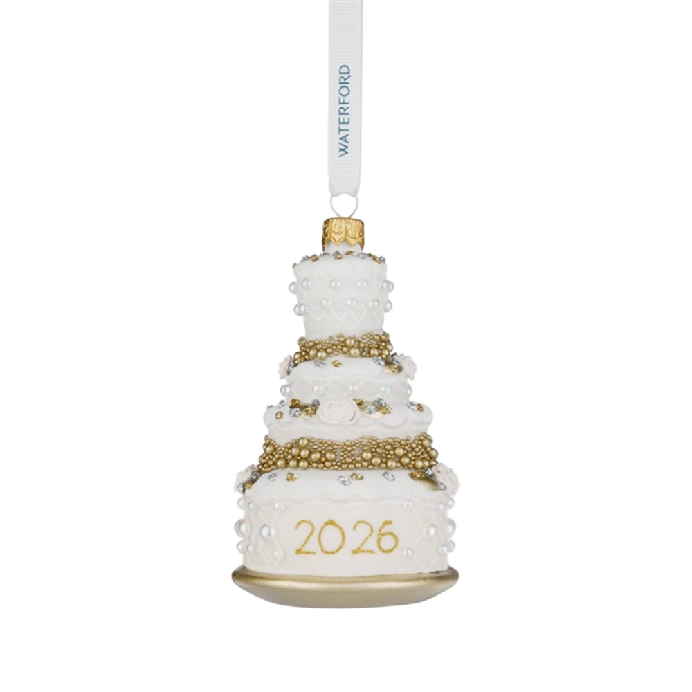 A white and gold tiered cake-shaped hanging ornament with pearl-like bead details, the year '2026' in gold on the base, and a white hanging ribbon printed with the brand name WATERFORD.