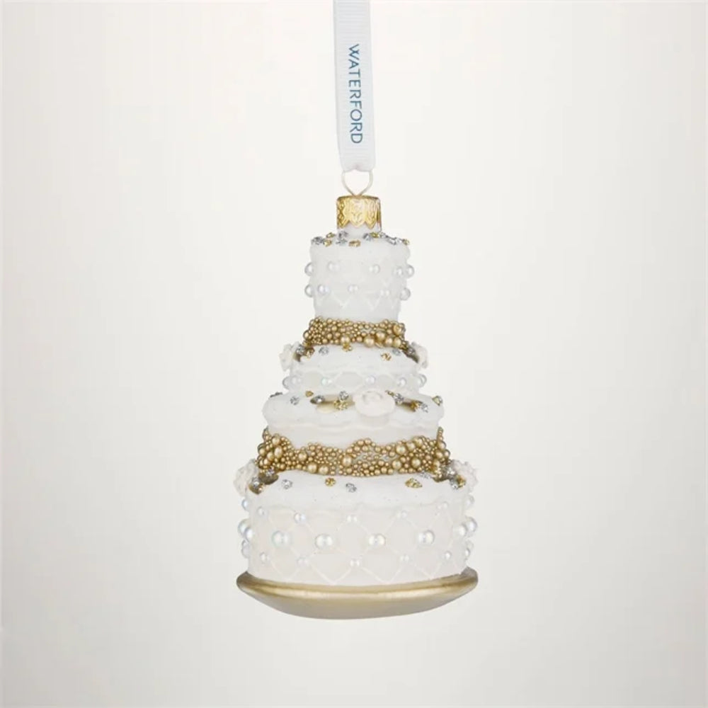 A white and gold tiered cake-shaped hanging ornament with pearl-like bead details and a white hanging ribbon printed with the brand name Waterford.