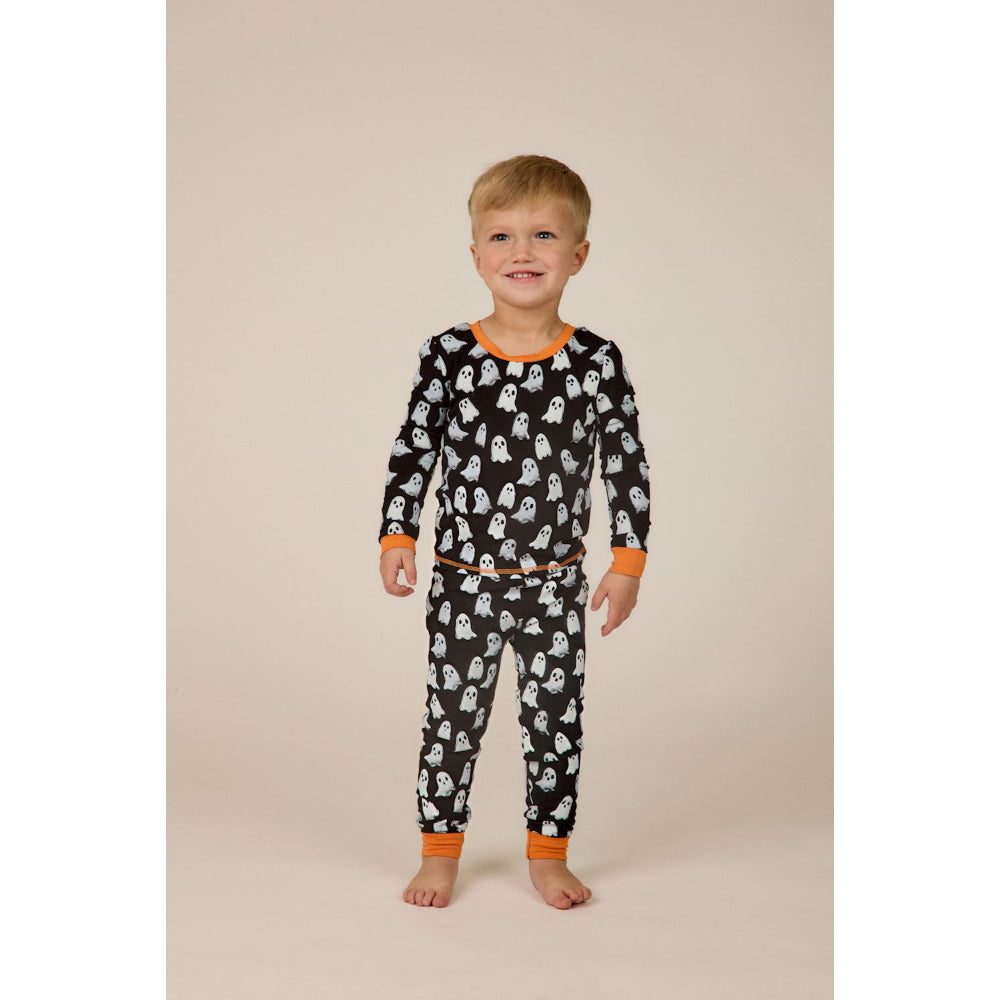 Child wearing a black pajama set with ghost pattern on a beige background