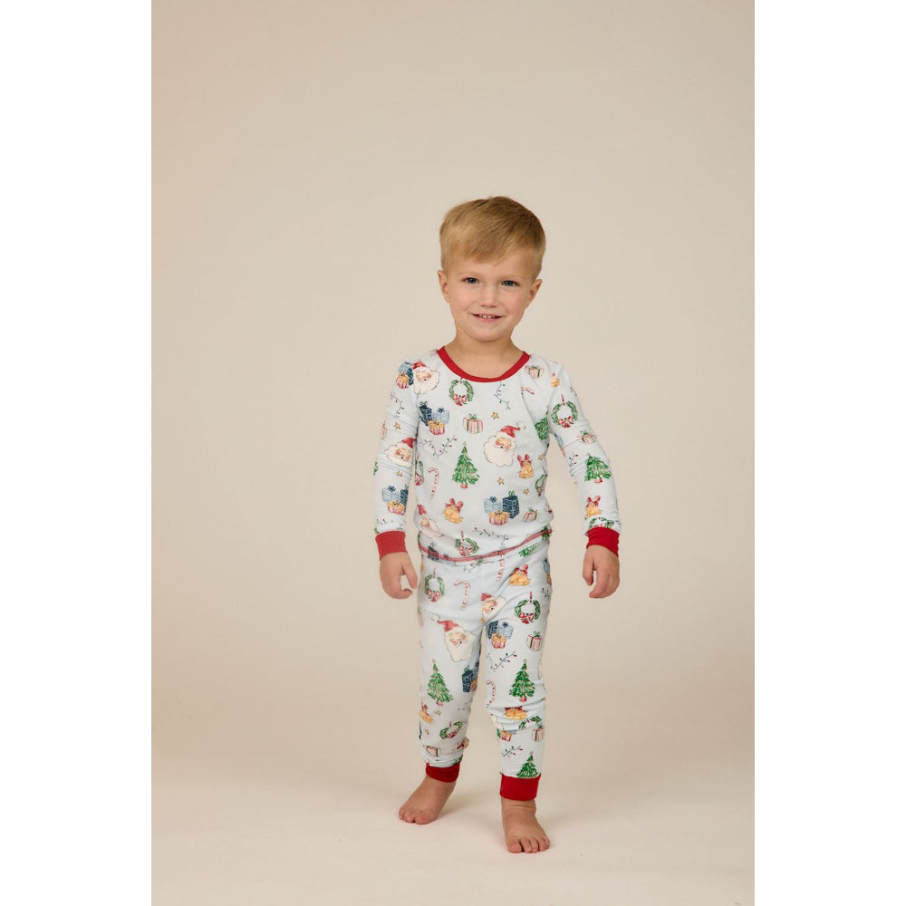 Child wearing a Blue christmas-themed pajamas on a beige background.