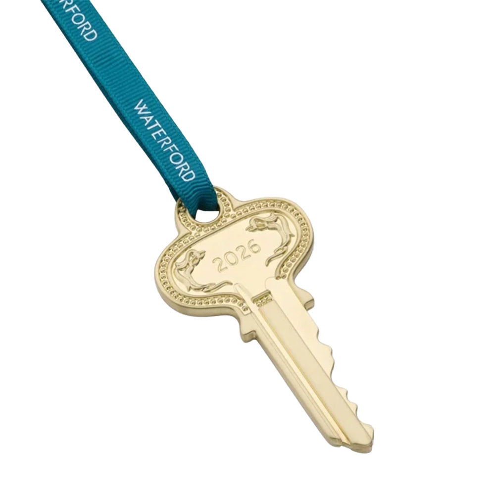 A gold-colored key-shaped ornament or medal hanging from a teal ribbon printed with the brand name 'WATERFORD' in white, set against a white background.