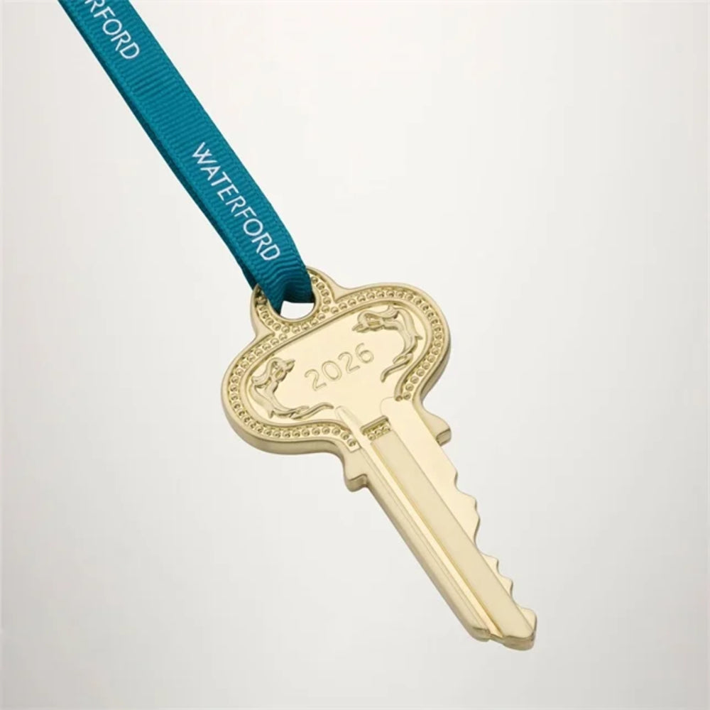 A gold-colored key-shaped award medal engraved with '2026' and a blue ribbon strap printed with 'WATERFORD', shown on a light gray background.
