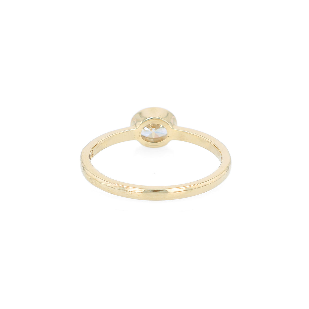 A delicate yellow gold ring featuring a bezel-set oval diamond, shown against a plain white background.
