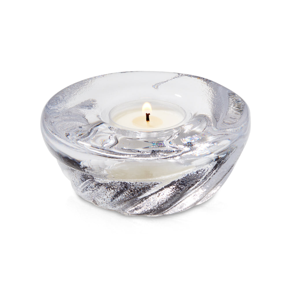 Clear glass candle holder with a lit candle on a white background