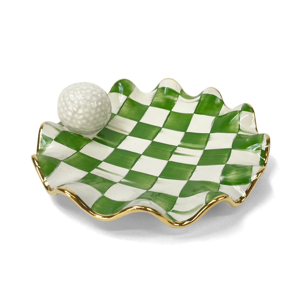 A angled side photo of a green and white check MacKenzie Childs ceramic golf ball wavy plate on a white background