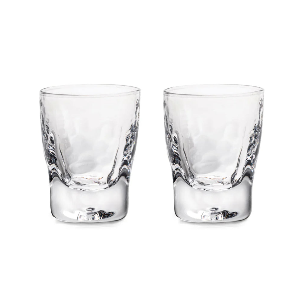 A set of two glass shot glasses on a white backround 