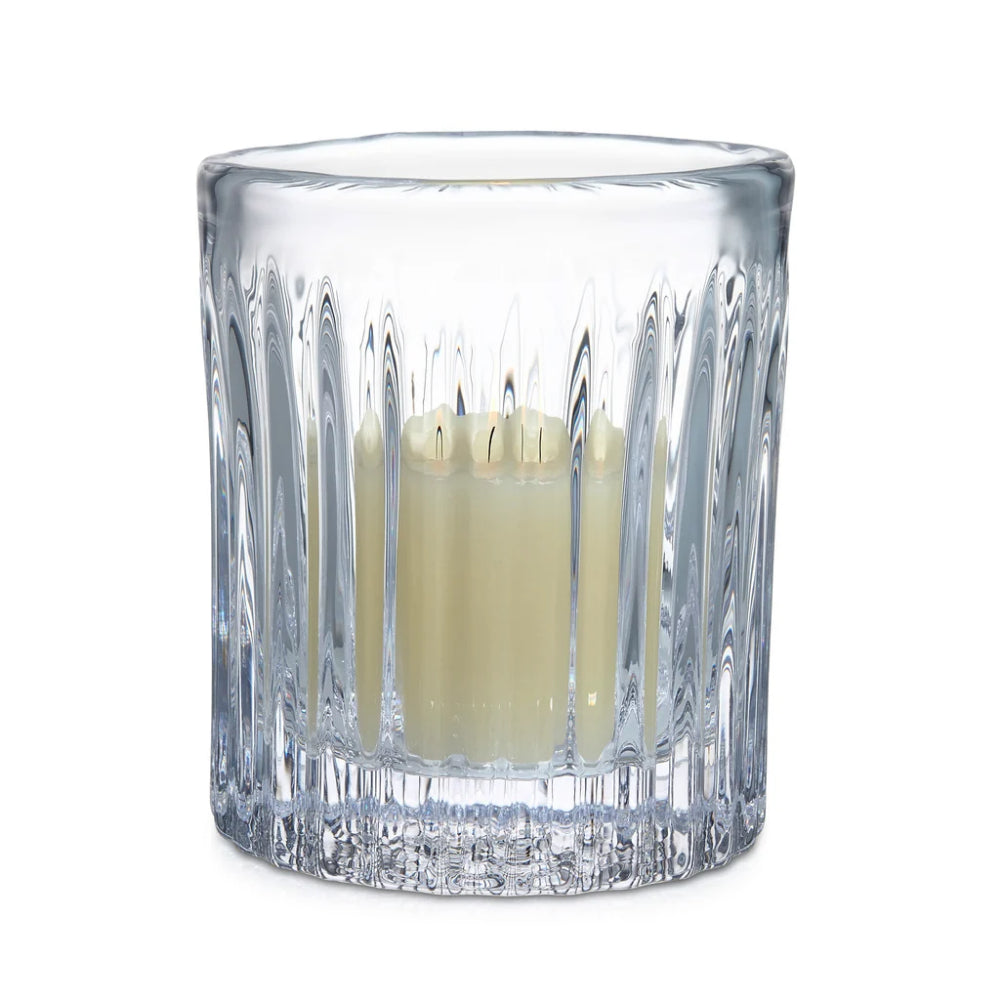 Clear glass candle holder with a white candle on a white background