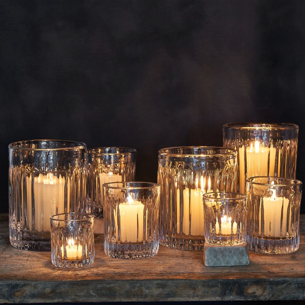 Set of glass candle holders with candles on a dark background