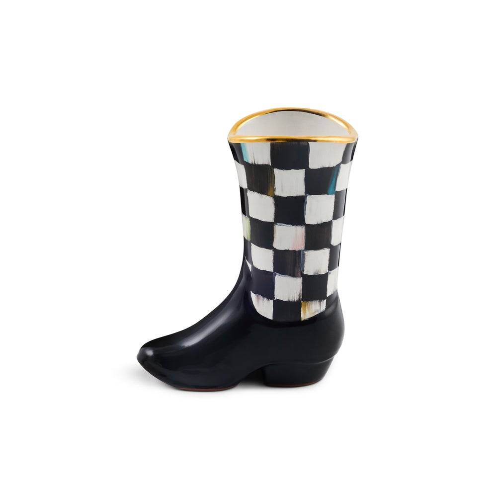 A ceramic cowboy boot planter from the MacKenzie Childs Lainey Wilson Collection, featuring a black and white checkerboard pattern on the shaft, a black polished finish on the foot, and gold rim accent.