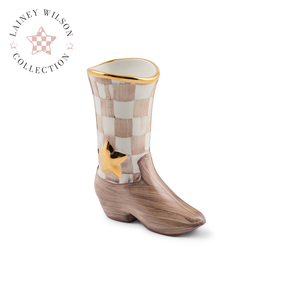 A ceramic cowboy boot planter from the Lainey Wilson Collection, featuring a brownish-pink and white checkerboard pattern on the shaft, a brown brushed texture lower boot, and gold trim at the rim and as a decorative star accent.