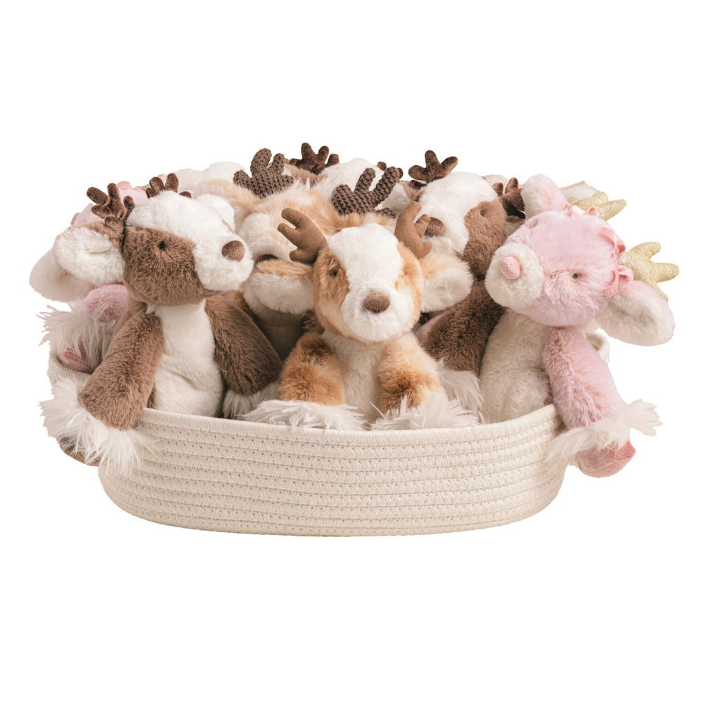 A collection of plush reindeer and deer stuffed animals in various colors like brown, white, tan, and pink, arranged inside a cream-colored woven basket on a solid white background.
