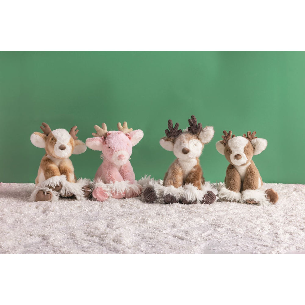 Four plush reindeer toys arranged side by side on a white textured rug against a solid green background. The reindeer include two brown-and-white ones and two pink-and-white ones, with varying antler sizes.