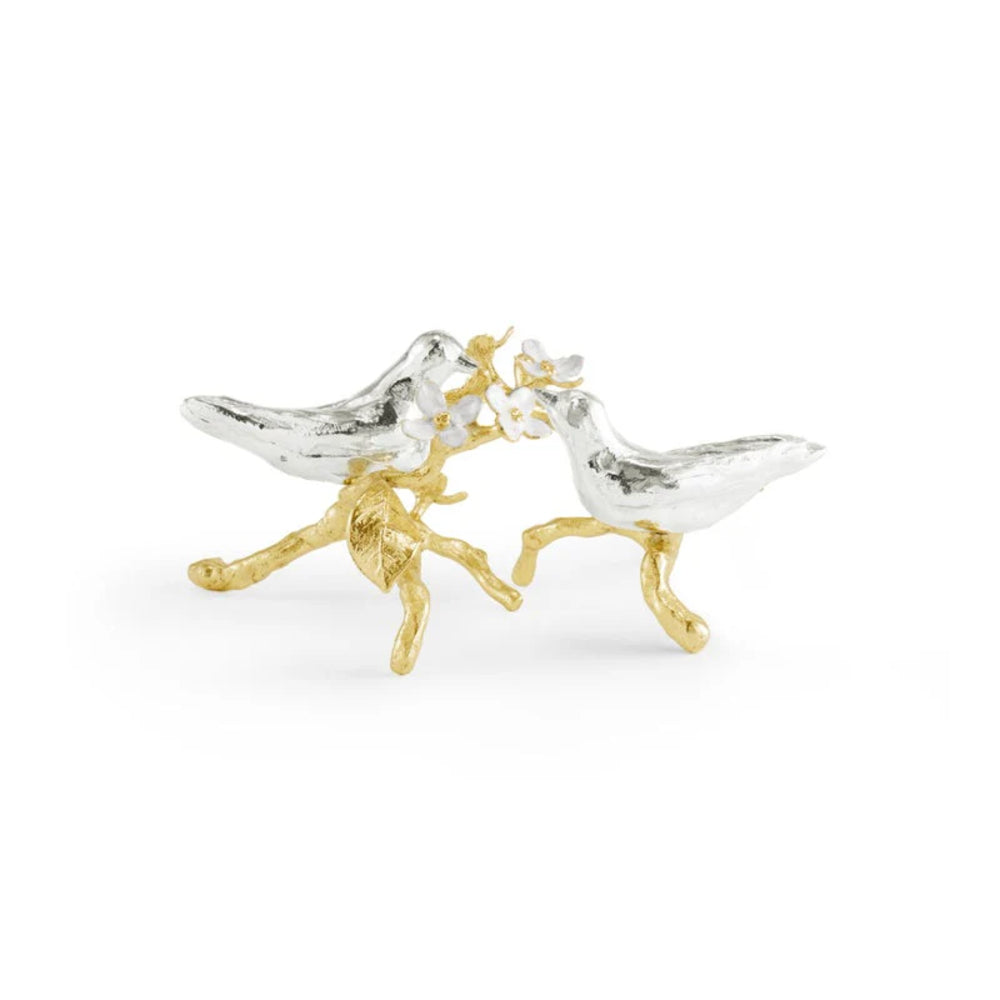 Pair of silver and gold bird-shaped figurines on a white background
