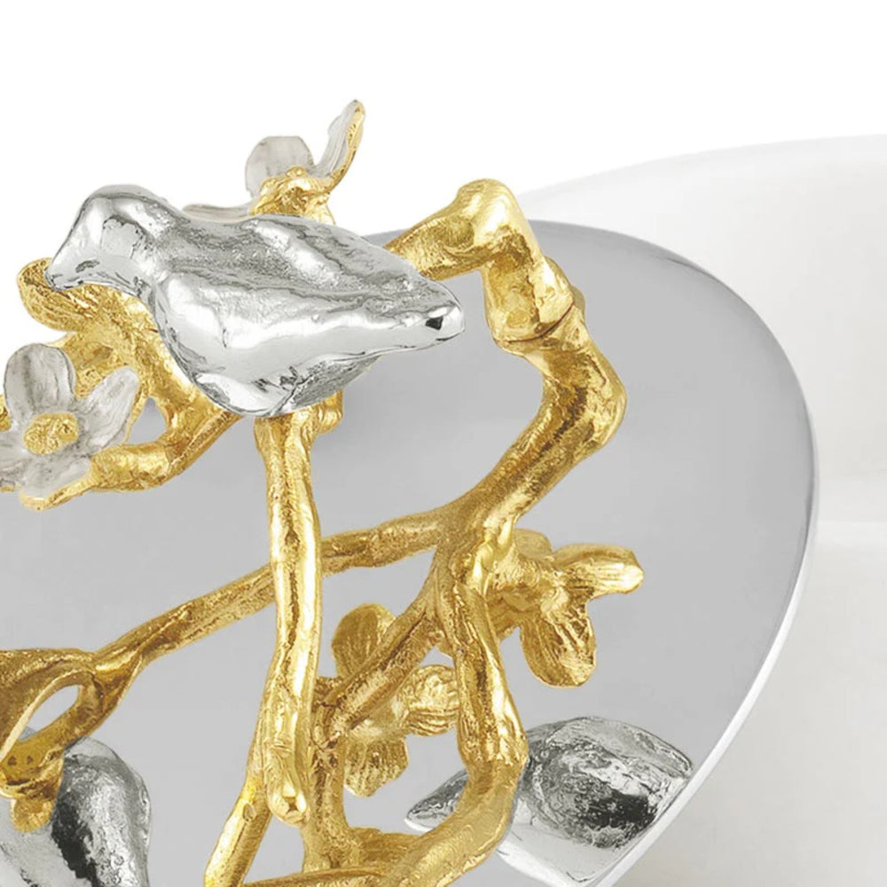 Close-up of a silver and gold jewelry piece with floral designs on a white background.
