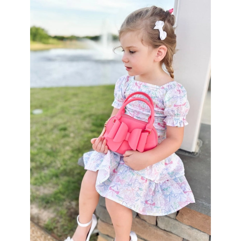 Young girl holding a pink handbag by a waterfront