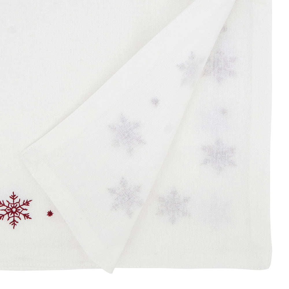 A folded white fabric item, likely a baby blanket or towel, featuring embroidered silver snowflakes and a red snowflake motif on the corner.