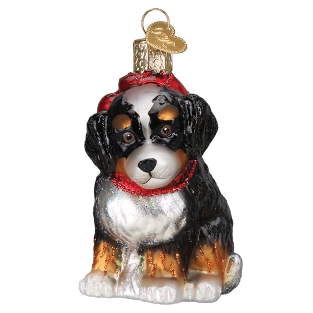 Glass ornament of a dog wearing a red hat and scarf on a white background.