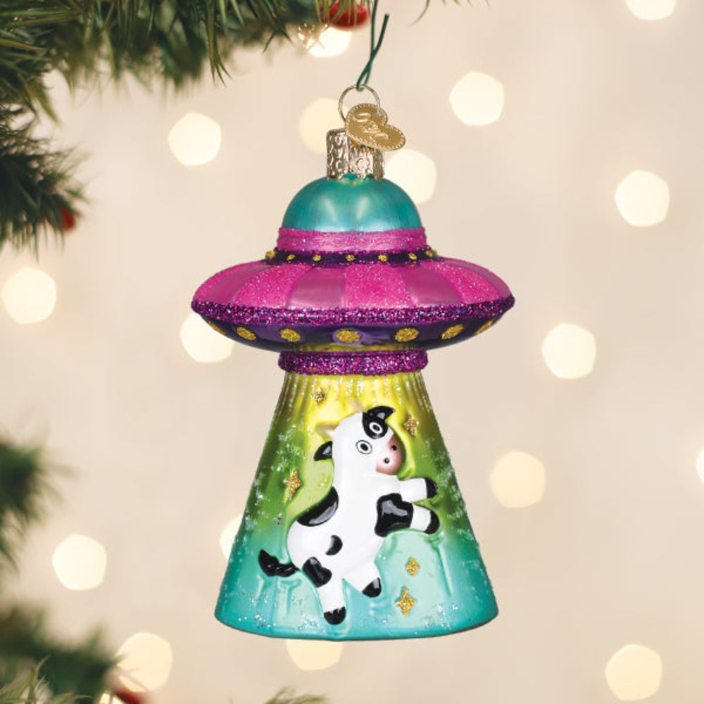 Christmas ornament with a cow inside a UFO on a decorated tree.