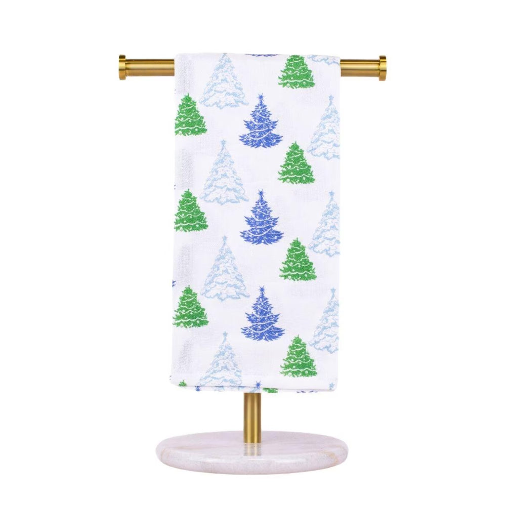 A white towel with a Christmas tree pattern in green and blue, hanging from a gold metal stand with a round marble base on a white background.