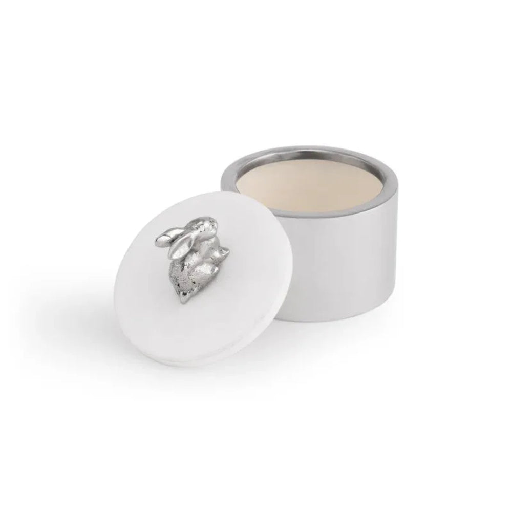 Small white container with a silver leaf-shaped object on a white background