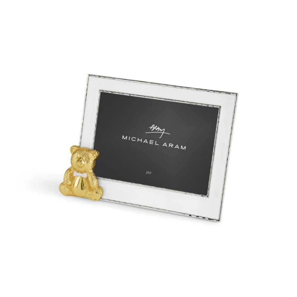 Right  angled side photo of a silver picture frame with a gold teddy bear ornament on a white background