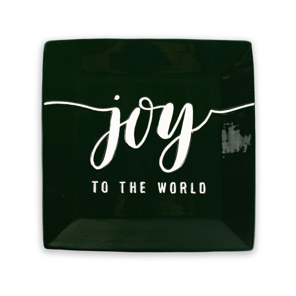 A square dark green ceramic plate with white text that reads 'joy TO THE WORLD' on a plain white background.