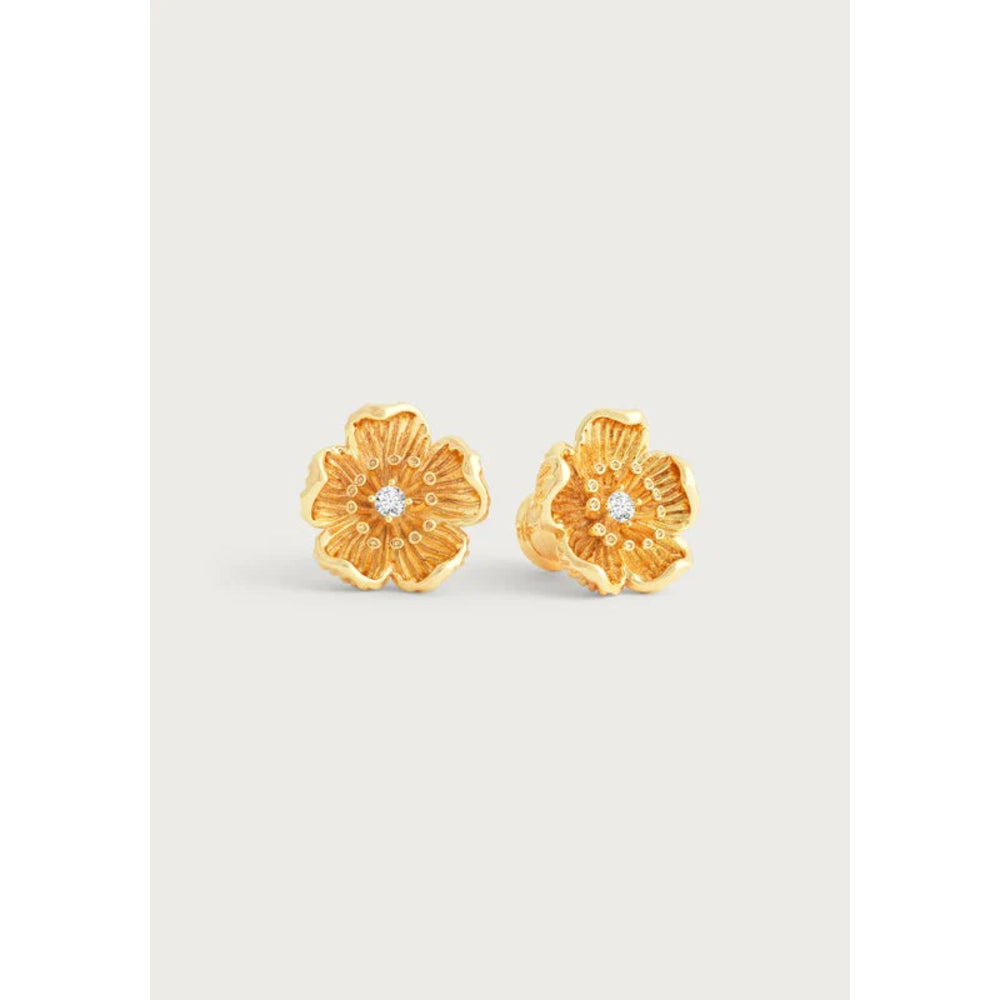 A pair of gold flower-shaped stud earrings with a small clear gemstone in the center, displayed on a light gray background.