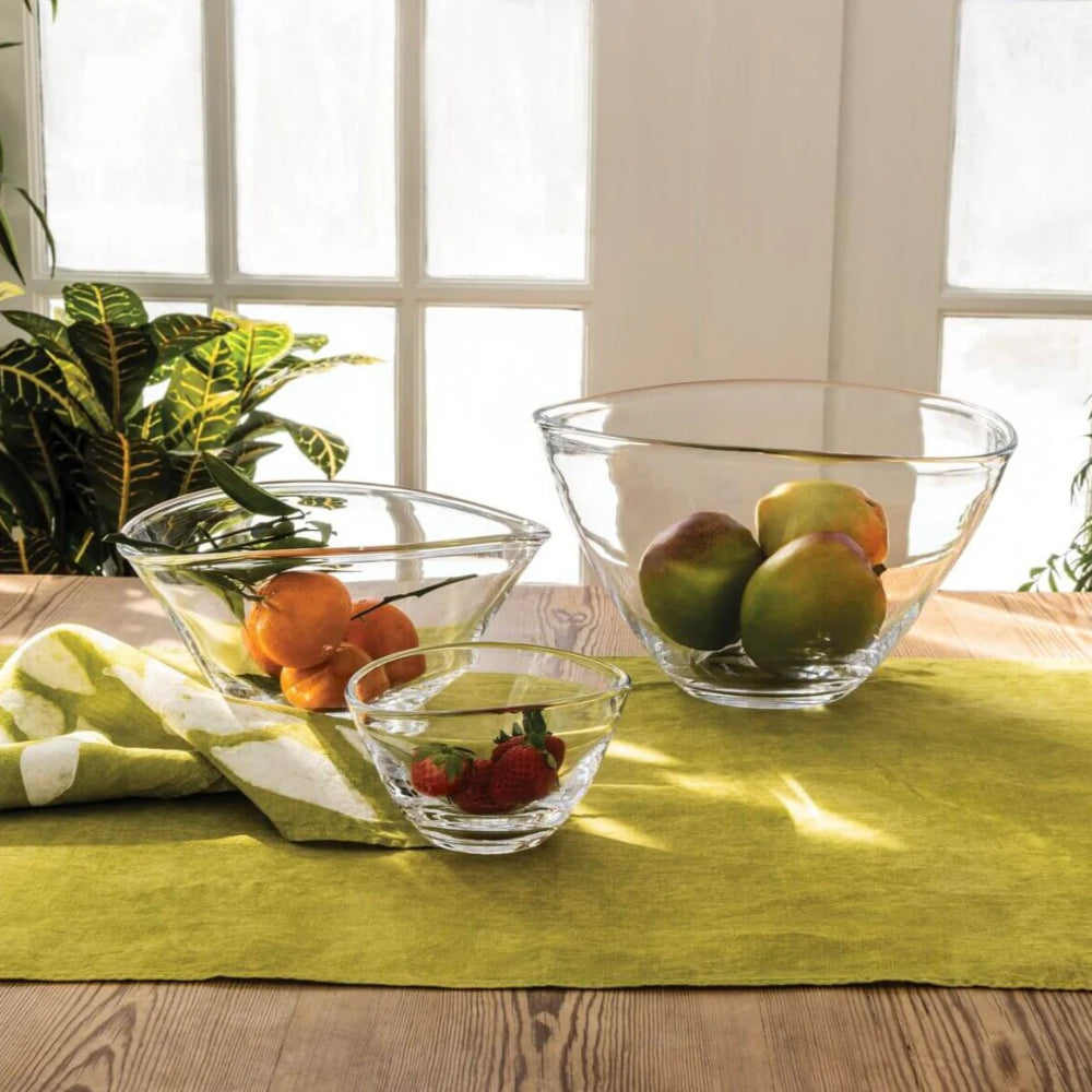 Clear glass bowls on a wood table with a green table runner with a white framed door in the backround. 
