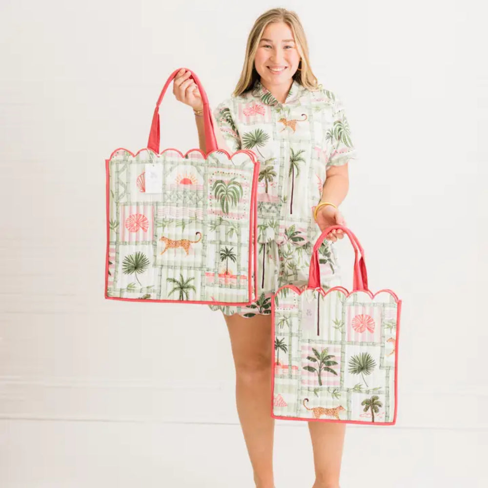 Woman holding two matching tote bags with a tropical design on a white background