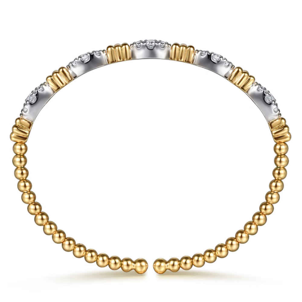 A two-tone gold and silver bangle bracelet with a beaded lower section, textured cylindrical upper segments, and a row of small clear stones on a plain white background.
