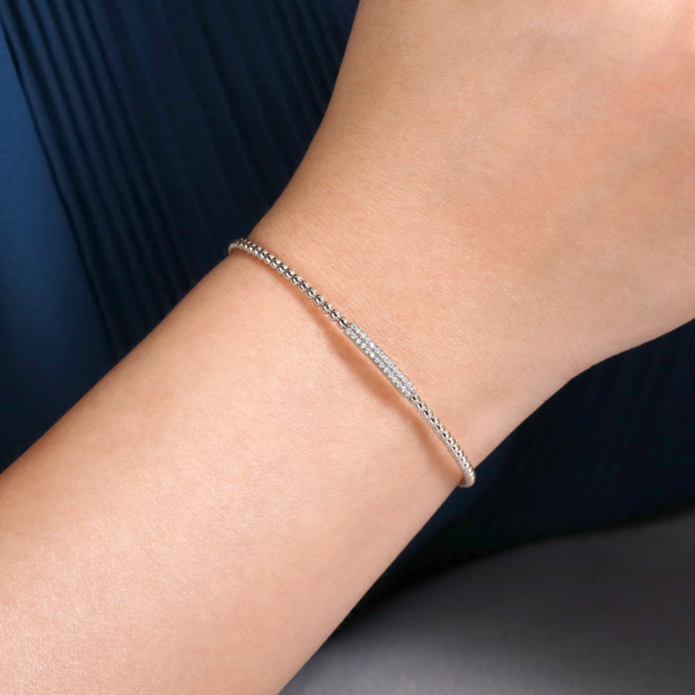 Silver bracelet on a person's wrist with a dark blue fabric background