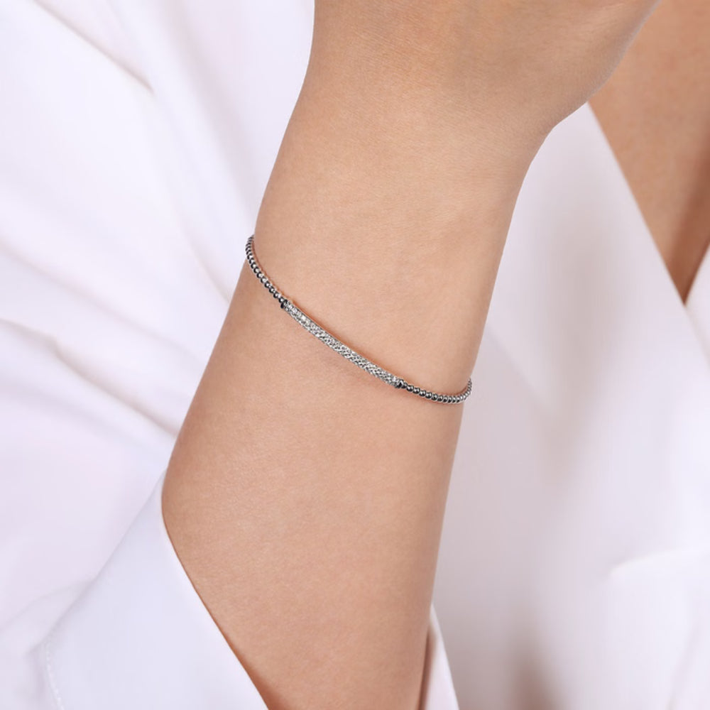 Silver anklet on a person's ankle against a white background