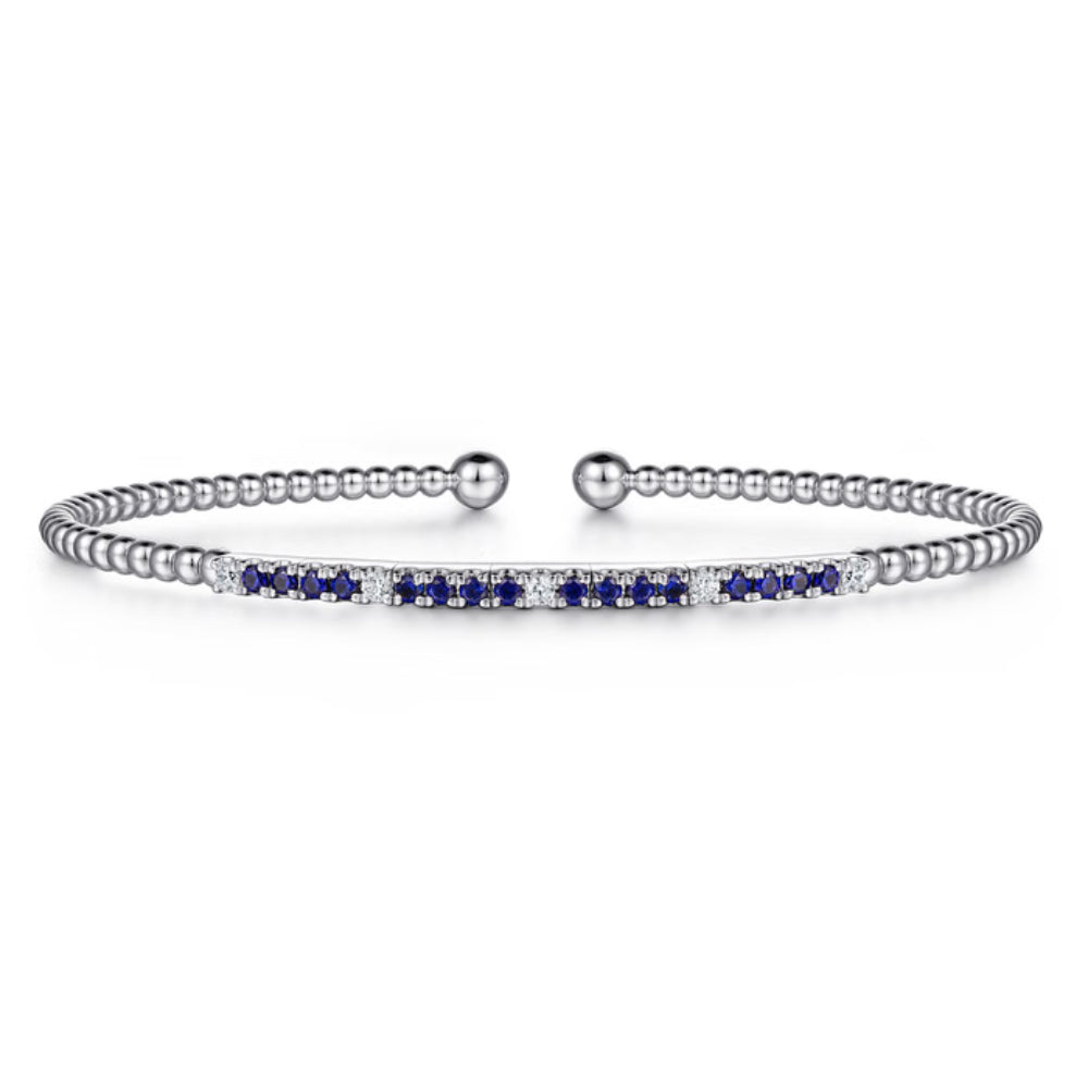 Silver bracelet with blue and clear gemstones on a white background