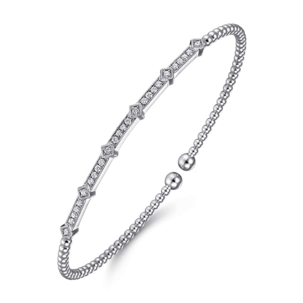 A silver-toned bangle bracelet featuring a central channel of small clear stones set in a diamond-shaped pattern, with a beaded outer band and a ball closure, shown on a white background.