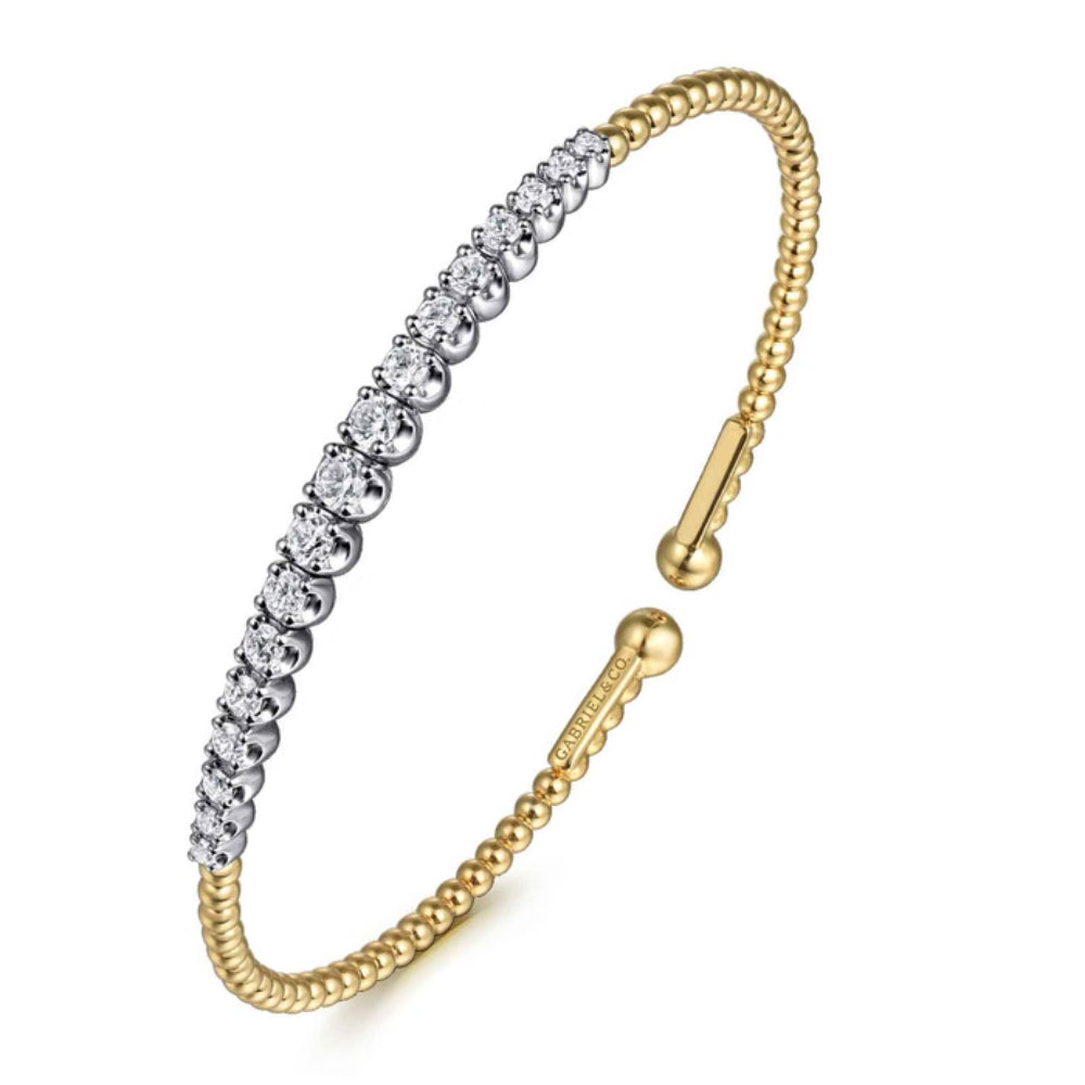 A two-tone gold and silver bangle bracelet featuring a row of clear cubic zirconia stones on one half, with a textured gold beaded band and a sliding clasp on the other.