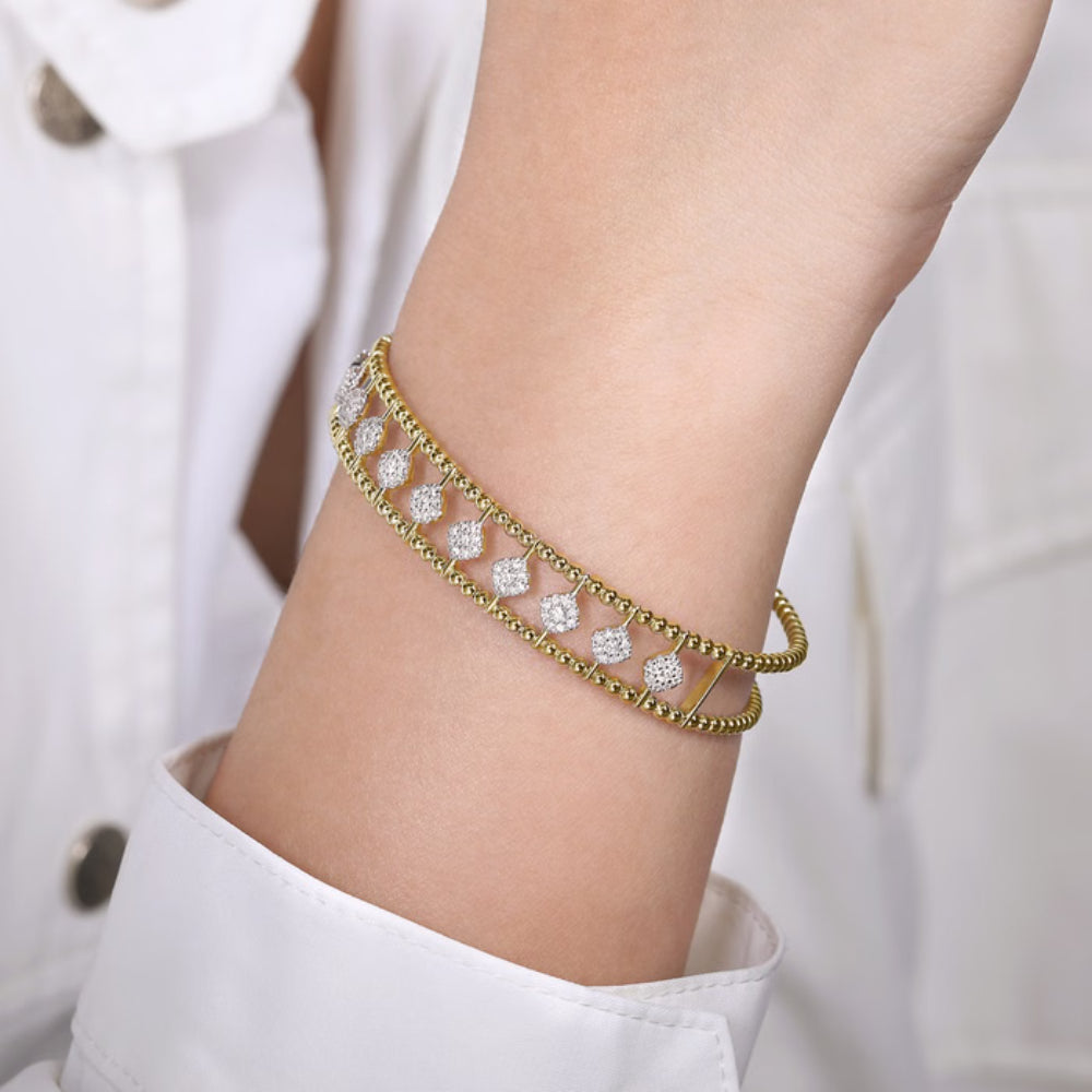 Gold bracelet with diamonds on a person's wrist against a white background