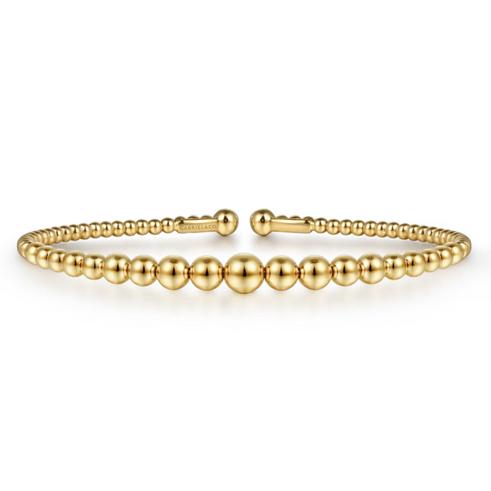 A gold beaded bracelet with a polished finish and a sliding clasp, displayed on a clean white background.
