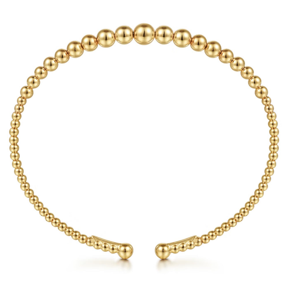 A gold beaded cuff bracelet with a polished finish, displayed in a circular shape against a clean white background.