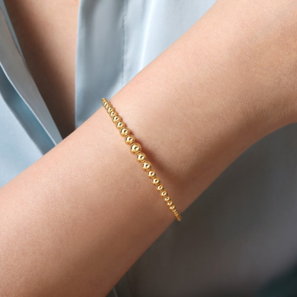 Gold bracelet on a person's wrist with a neutral background