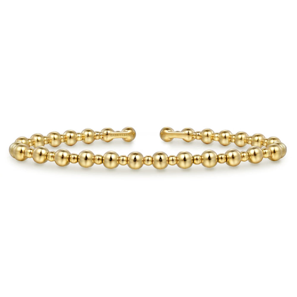 A gold beaded cuff bracelet with polished spherical beads and an open end, shown on a plain white background.