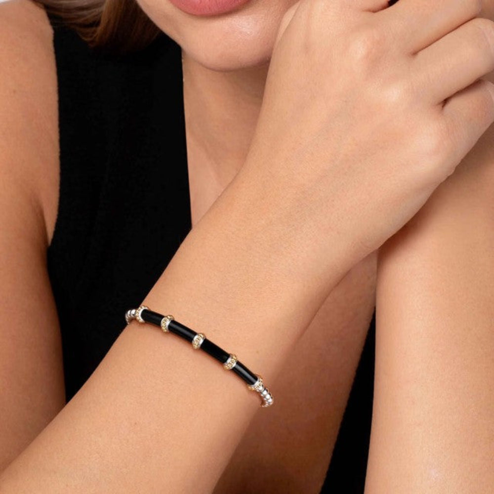 Close-up of a person wearing silver, gold and black bangle bracelet 